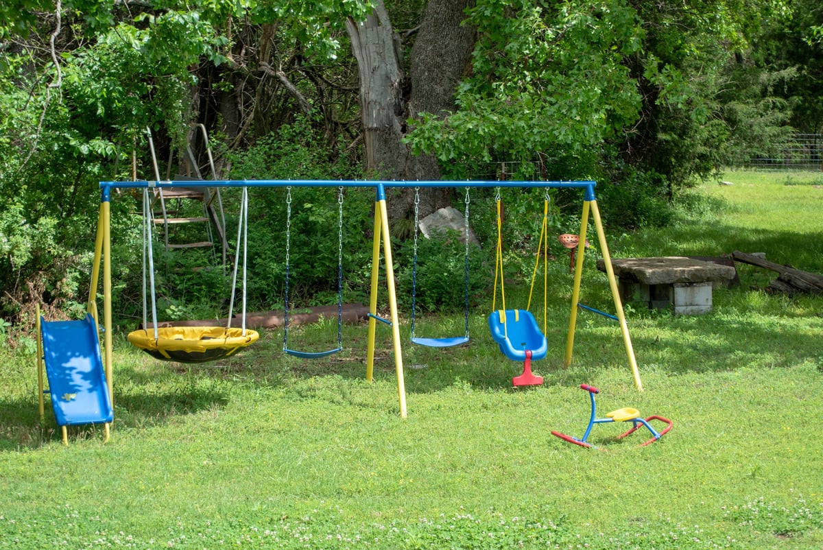 A colorful playset and rocking toy on a lush green lawn