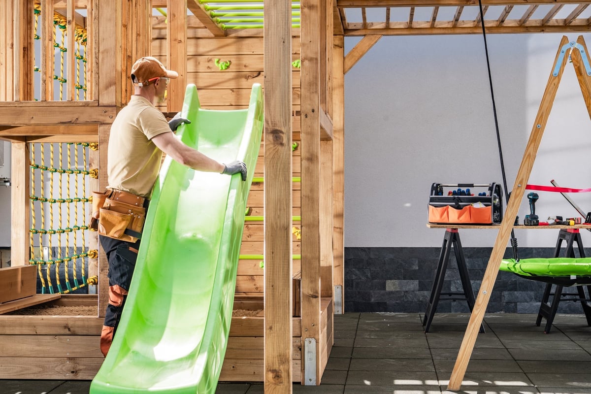 A skilled technician positioning a swing set slide during professional installation